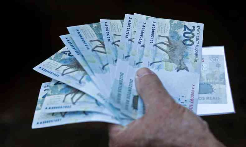Nesta foto de arquivo tirada em 2 de setembro de 2020, um homem segura notas de duzentos reais depois que o Banco Central do Brasil as emitiu em Braslia, em 2 de setembro de 2020.