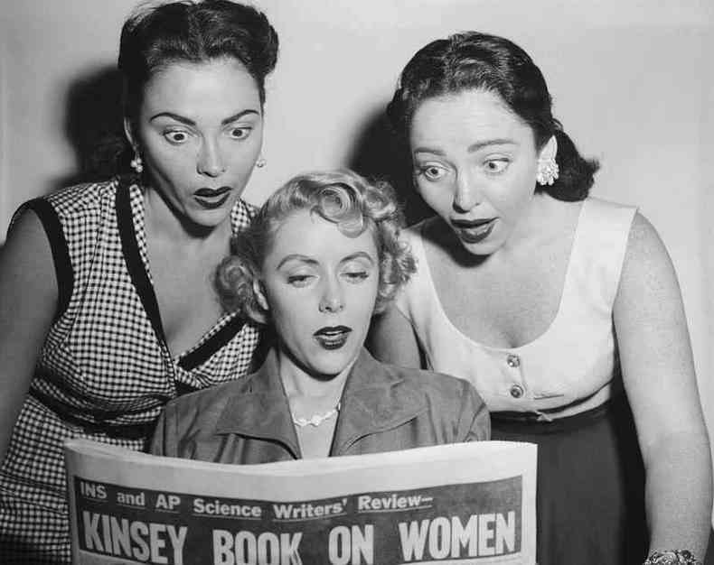 Trs mulheres lendo jornal