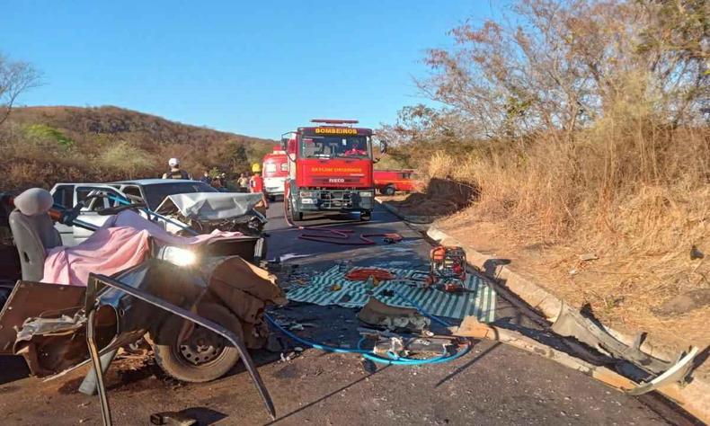 Dois carros destrudos no meio da rodovida aps coliso frontal. Carro do Corpo de Bombeiros aparece ao fundo da foto. 