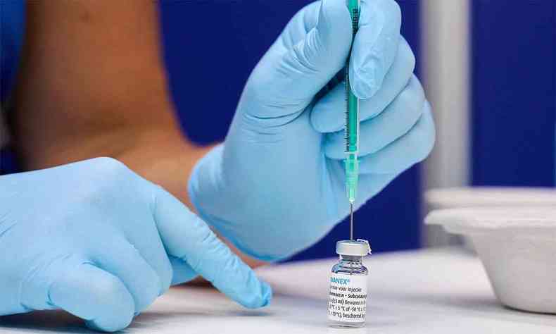 Enfermeira coloca seringa sobre frasco de vacina