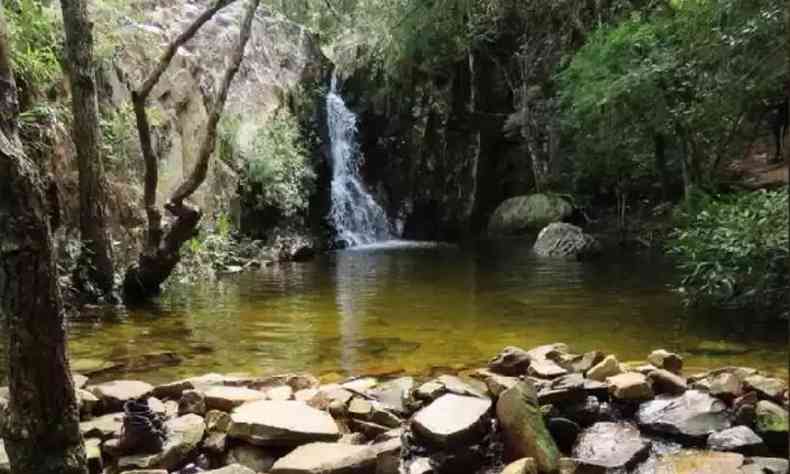 Imagem de uma cachoeira na Serra So Jos. H um monte de pedras na parte inferior da imagem e vegetao nativa ao redor
