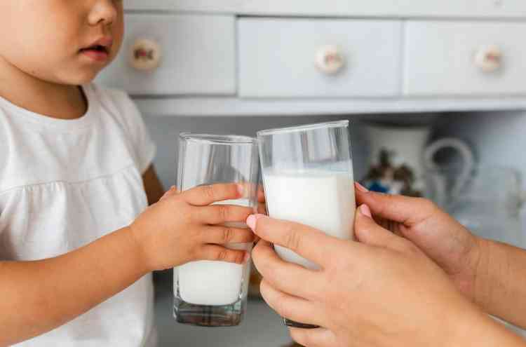 Adulto e criana segurando copos de leite