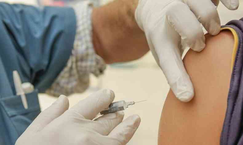 Profissional de sade aplica vacina no brao de outra pessoa