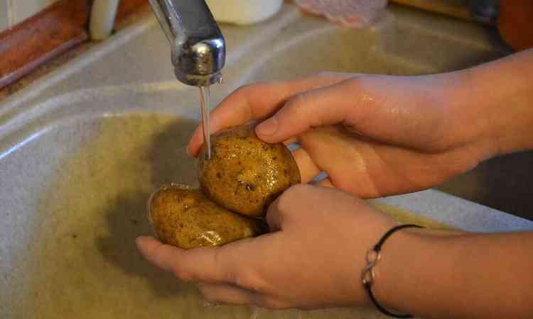 mo lavando batata inglesa em uma pia de cozinha