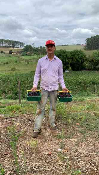Aliandro da Silva, produtor de amoras, segurando dois cestos cheios da fruta
