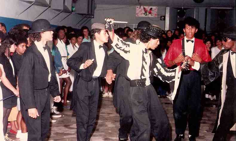 Dançarinos de black music fazem passos, em baile em Venda Nova, vestidos de terno e observados por jovens. Um dançarino veste figurino de Michael Jackson