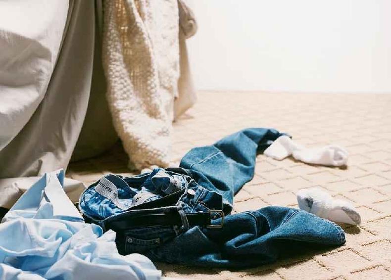 Jeans jogados ao lado de cama