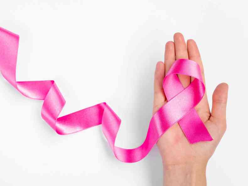 Mo direita feminina segura lao rosa, alertando sobre importncia da campanha 'Outubro Rosa' e que diagnstico precoce com mamografia permite tratamento mais eficaz