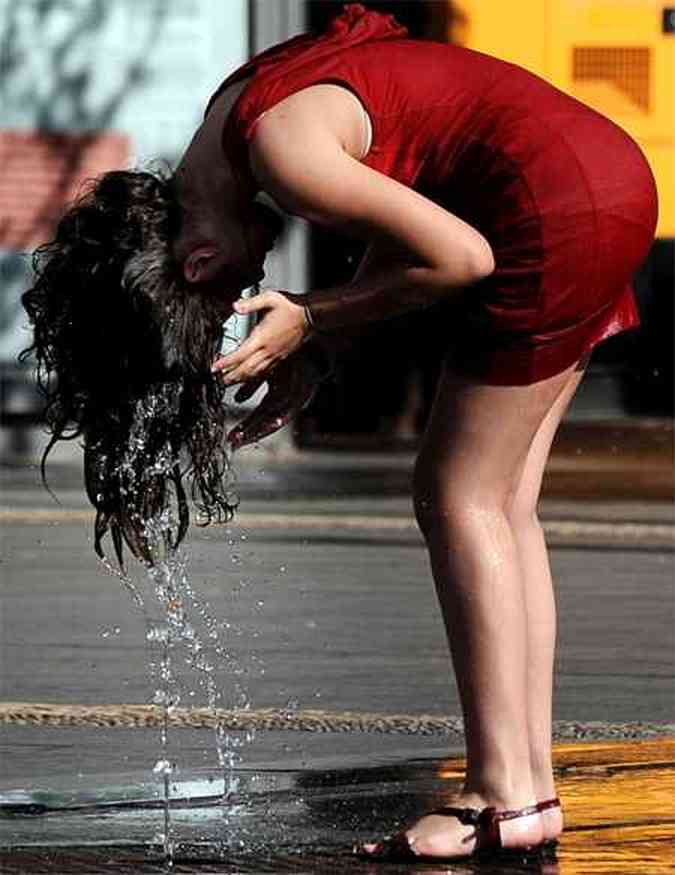 Mulher se refresca em rua na Espanha(foto: CRISTINA QUICLER / AFP)