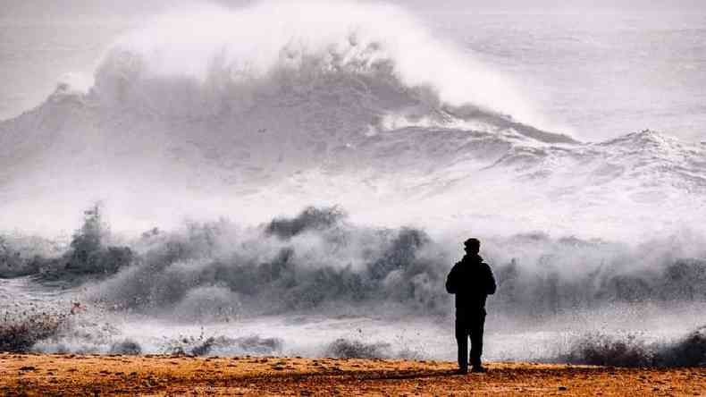 Homem olhando para ondas enormes em Nazar