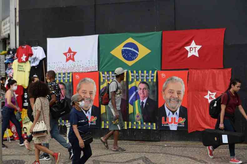 Toalhas do Bolsonaro e Lula e bandeiras do PT e do Brasil expostas em um painel