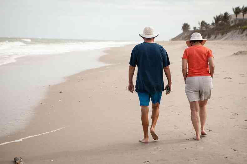 casal de idosos caminha em praia