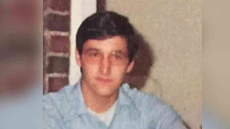Um jovem branco de culos e camisa em uma foto antiga, em baixa resoluo.