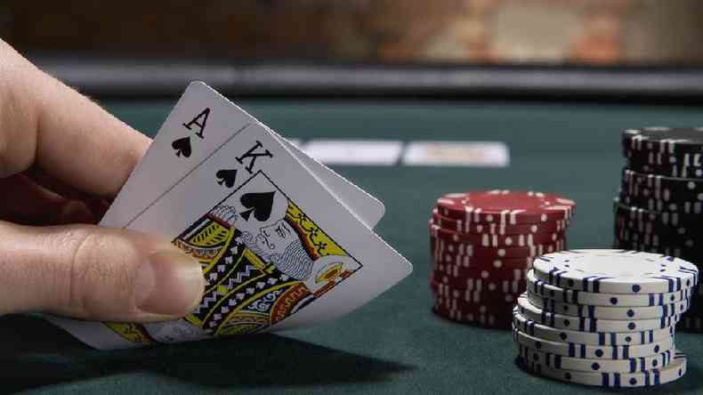 Close de uma mo segurando duas cartas durante um jogo de pquer