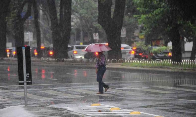 Pedestre atravessando avenida de baixo de chuva em Belo Horizonte