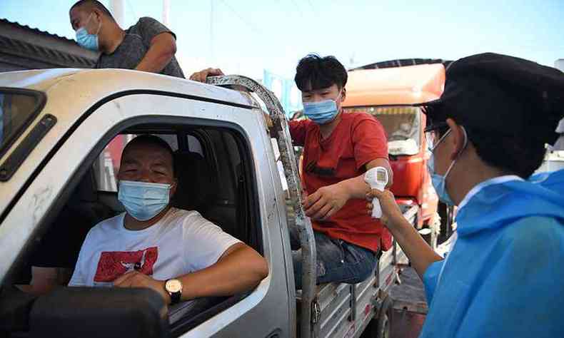 Ocupantes de carro passam por checagem de temperatura antes de entrar no mercado de Xinfadi, em Pequim(foto: Noel Celis/AFP)