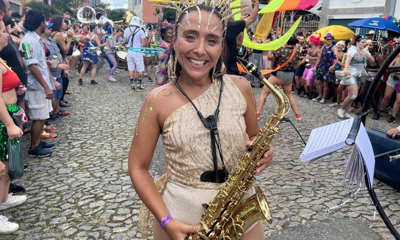 integrante da Estagiários Brass Band carrega saxofone em desfile