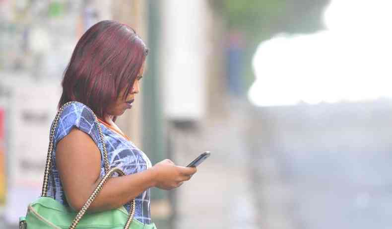 Mulher usando celular na rua.