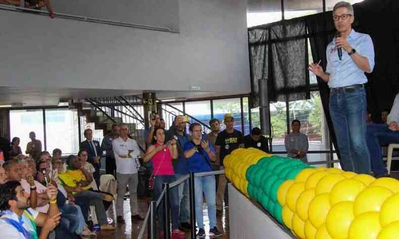 Zema no palco, ao microfone, diante de uma plateia