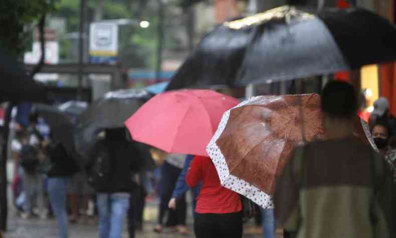 Pessoas andam com guarda-chuva pelo Centro de BH