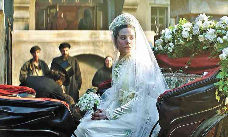 Sentada em carruagem, atriz Alyona Mikhailova, vestida de noiva e com buqu nas mos, olha para trs em cena do filme A esposa de Tchaikovsky