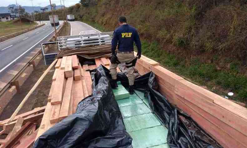Agente da PRF vistoria caminho onde foram encontradas mais de 3 toneladas de maconha entre a madeira transportada (foto: Polcia Rodoviria Federal/Divulgao)