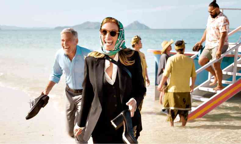 Julia Roberts sorri, em primeiro plano, e tem  sua direita George Clooney em cena do filme Ingresso para o paraso