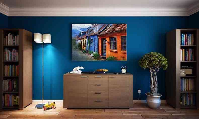 sala decorada com destaque para parede azul e estantes com livros e um rvore no vaso