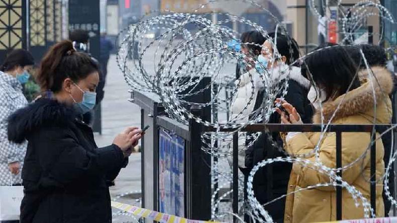 Moradores de Xi'an ficam ao lado de porto com arame farpado
