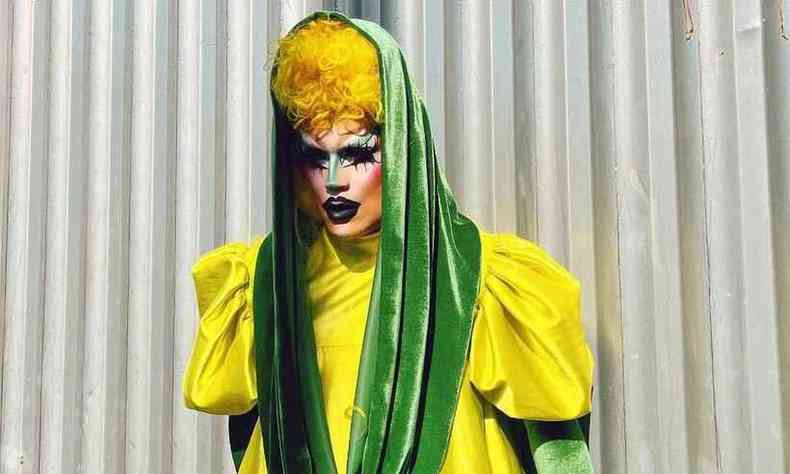 A Drag Queen Aquarela  branca e usa uma peruca amarela com um vestido amarelo e detalhes em verde, com inspirao em uma espiga de milho.