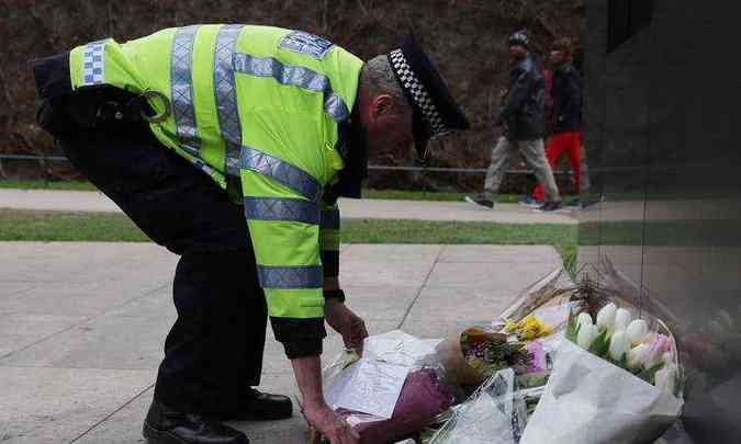 Um oficial da polcia coloca flores em homenagem s vtimas do atentado no Memorial da Polcia Nacional em Londres (foto: AFP / Daniel LEAL-OLIVAS )