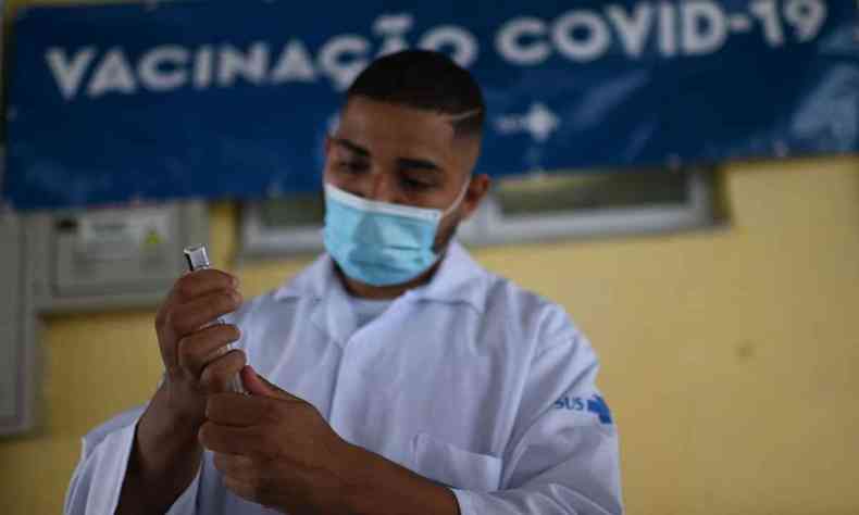 agente de sade usando mscara segura seringa e frasco de vacina contra COVID-19 no Rio de Janeiro em dezembro de 2021