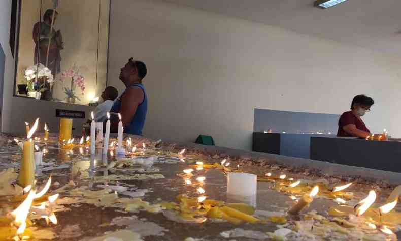 Velrio com velas acesas e pessoas rezando