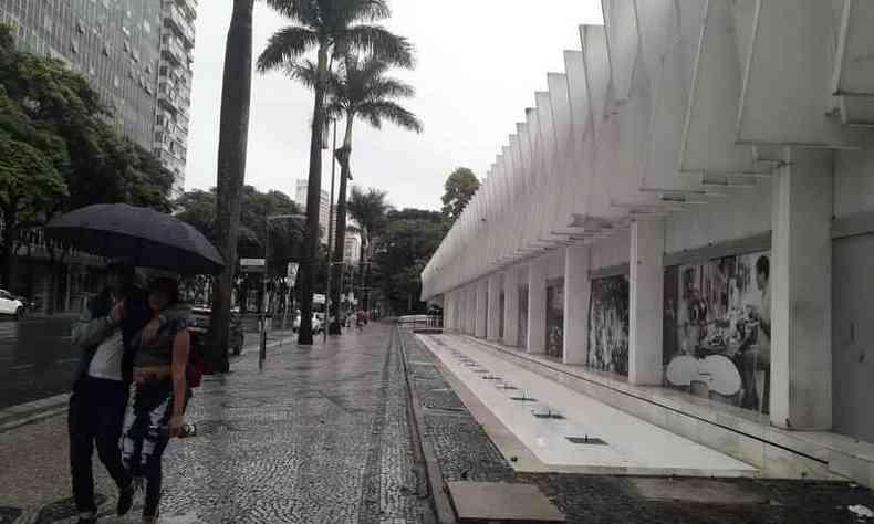 Casal com guarda-chuva andando na Avenida Afonso Pena 