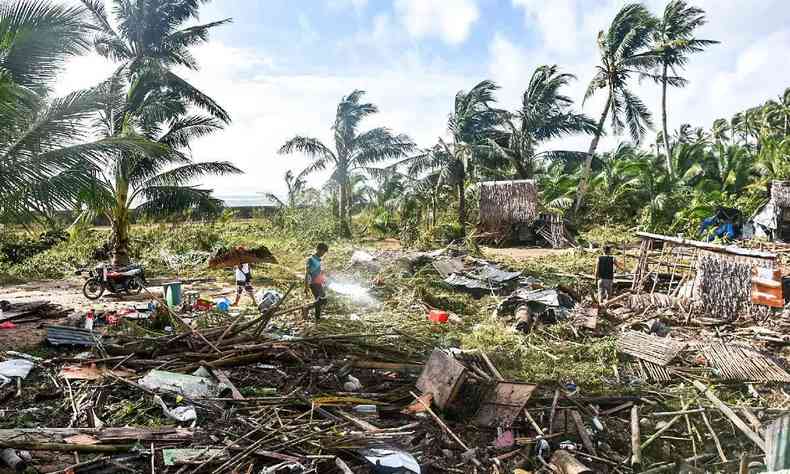 Os residentes passam por suas casas destrudas na cidade de Hernani, provncia de Samar Oriental, em 17 de dezembro de 2021, um dia depois que o Super Typhoon Rai atingiu as regies sul e centro das Filipinas
