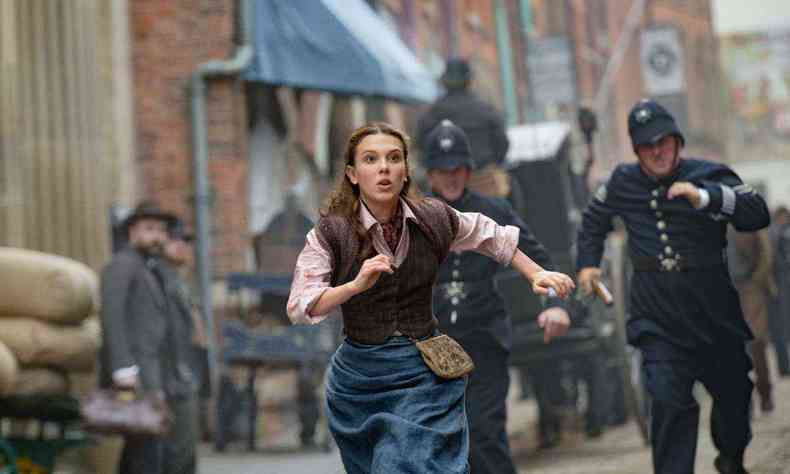 Millie Bobby Brown corre da polcia em cena do filme Enola Holmes 2
