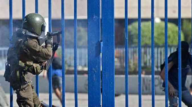 Membro da tropa de choque dispara contra estudantes em Santiago(foto: CLAUDIO SANTANA / AFP)