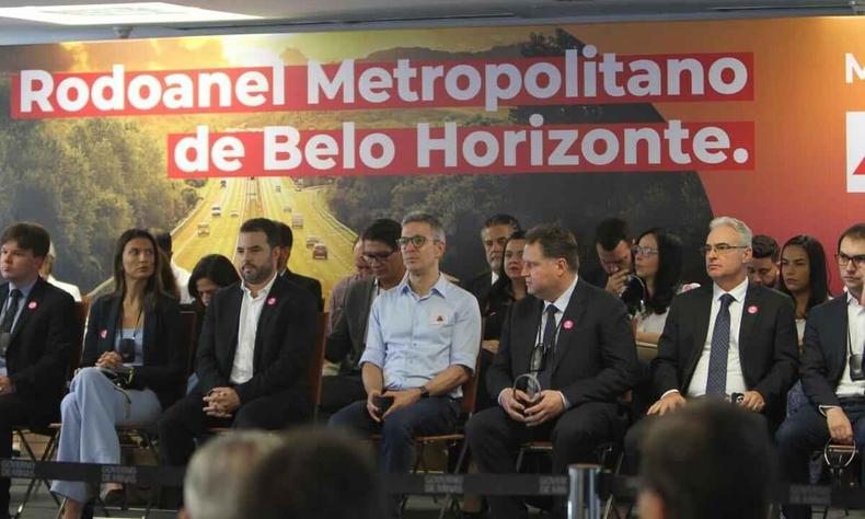 Governador Zema, no meio, em reunio sobre rodoanel. Ao fundo, paiel escrito ' Rodoanel Metropolitano de Belo Horizonte'