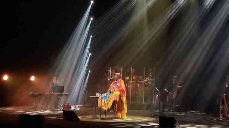 Milton Nascimento no palco, durante o show; ele est careca e veste uma roupa amarela com franjas