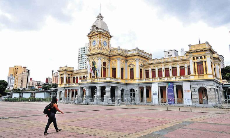 Mulher de máscara passa pela Praça da Estação. Ao fundo está o Museu de Artes e Ofícios, antiga estação ferroviária de BH 