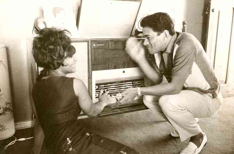 Em 1964, Elza Soares e Garrincha em casa, sentados no chão, seguram um disco em frente à radiola