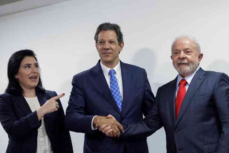 Fernando Haddad, ao lado de Simone Tebet, cumprimenta Lula; todos com expresso de felicidade
