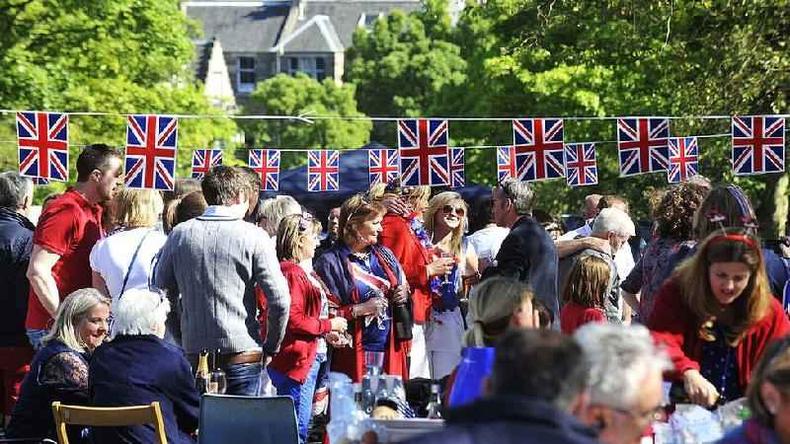 Pessoas reunidas na rua com bandeiras para celebrar o jubileu de diamante da rainha em Edimburgo em 3 de junho de 2012