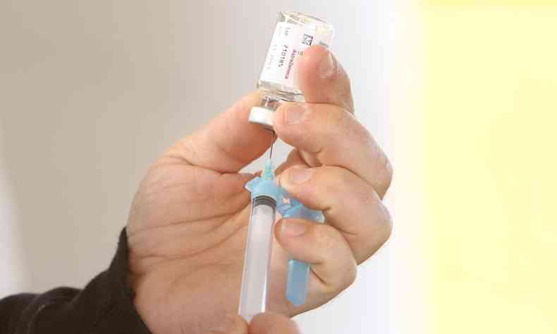 Enfermeira segurando seringa com frasco de vacina contra a COVID-19