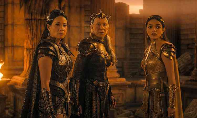 Atrizes Lucy Liu, Helen Mirren e Rachel Zegler, vestidas como deusas, esto lado a lado em cena do filme Shazam! Fria dos deuses
