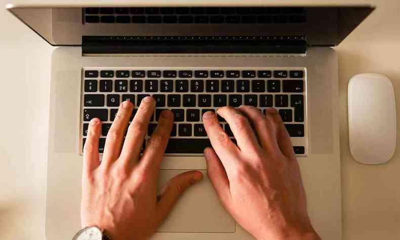 Imagem de um notbook com as mãos em cima do teclado