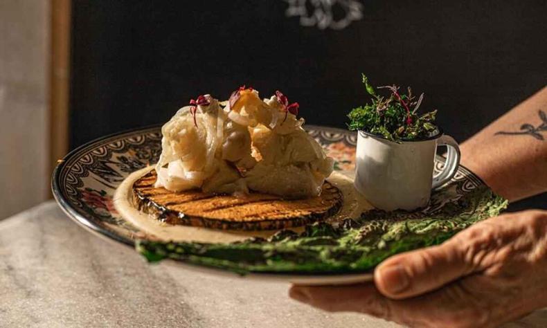 Prato Minha vida de menina é um dos mais bem vendidos do restaurante(foto: Divulgação/ Cozinha Santo Antônio; foto Luísa Macedo) prato Minha vida de meninda, composto por posta de bacalhau de 300g com angu de milho criolo, lua de abóbora, couve crocante e traguinho de feijão preto.