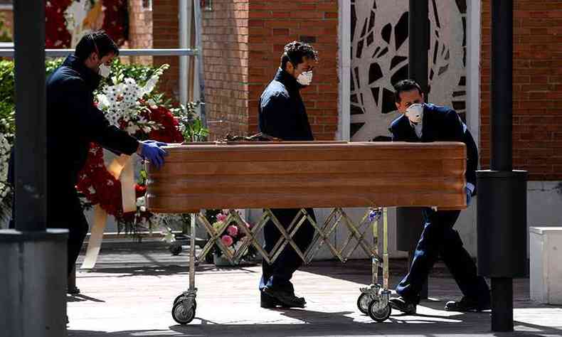 Usando mscaras e luvas, funcionrios de funerria levam caixo para cemitrio em Madrid(foto: Oscar Del Pozo/AFP)