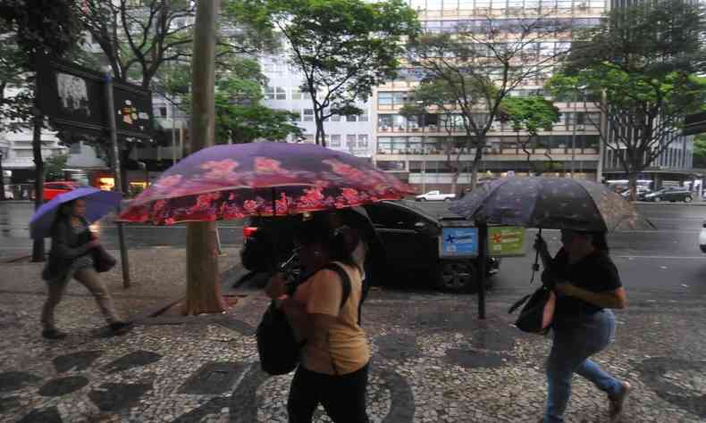 Pessoas usam guarda-chuva na rua