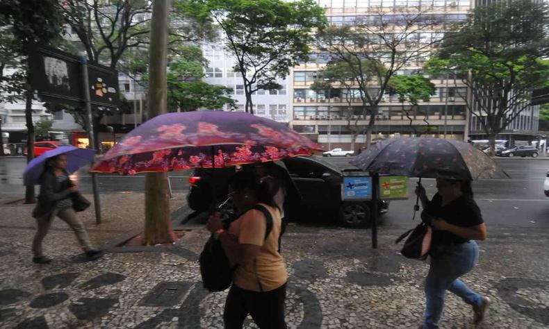 Pessoas usam guarda-chuva na rua